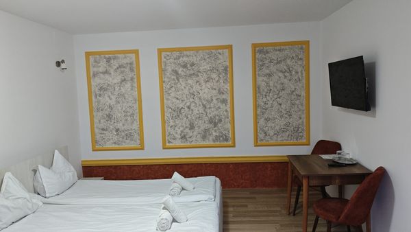 Habitación de Casa Marko con cama doble, paneles decorativos dorados en la pared, TV y mesa